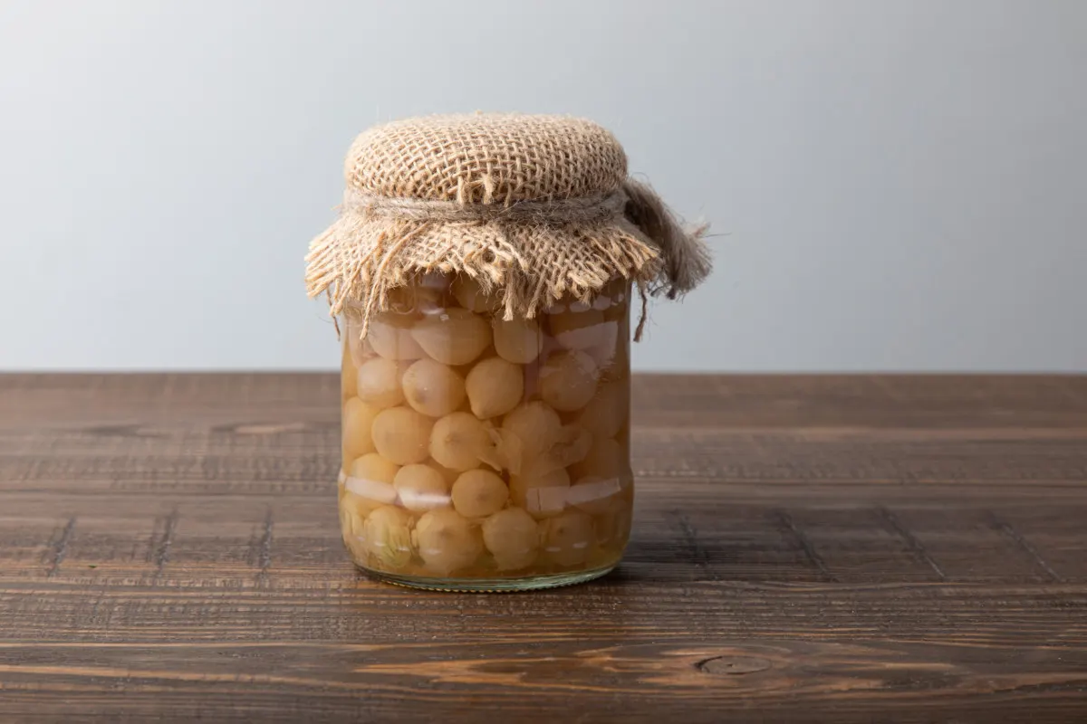 Jar filled with pickled pearl onions, burlap top