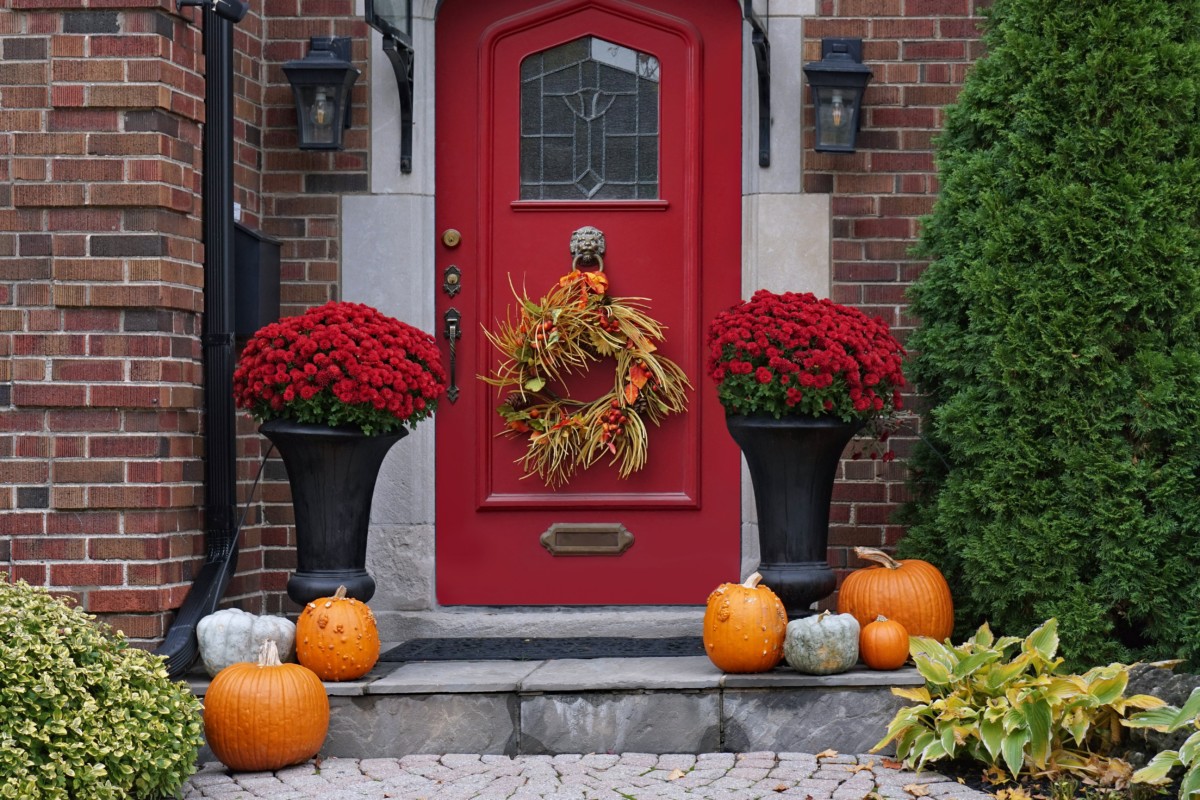 Front steps of a house decorated for fall, including several pumpkins.