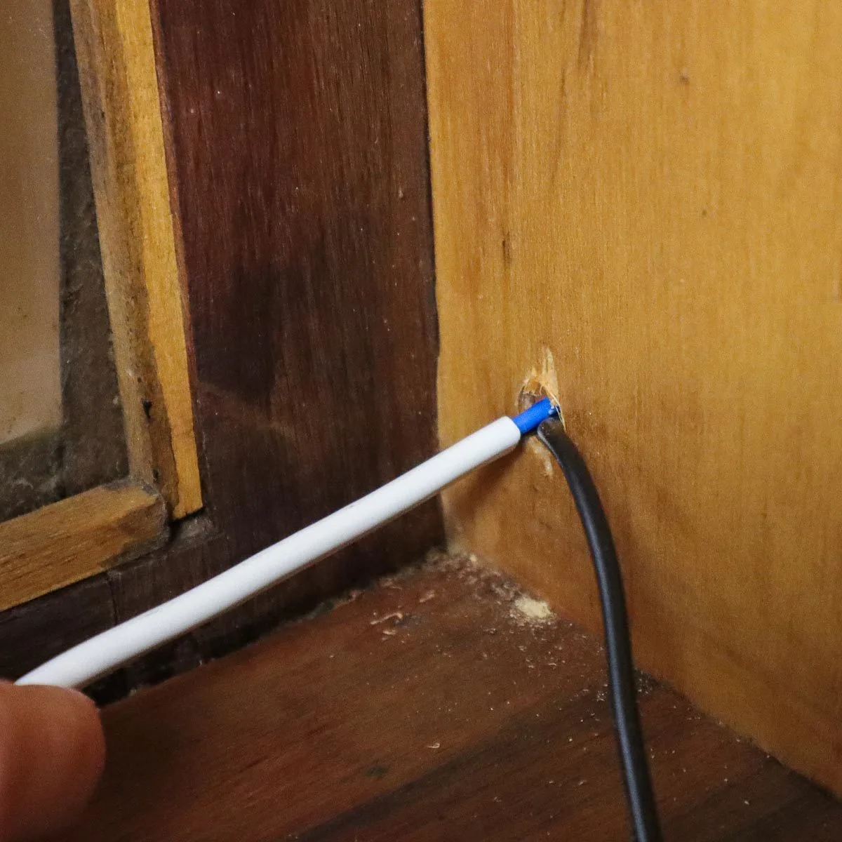 Plug being fed through hole in cabinet.