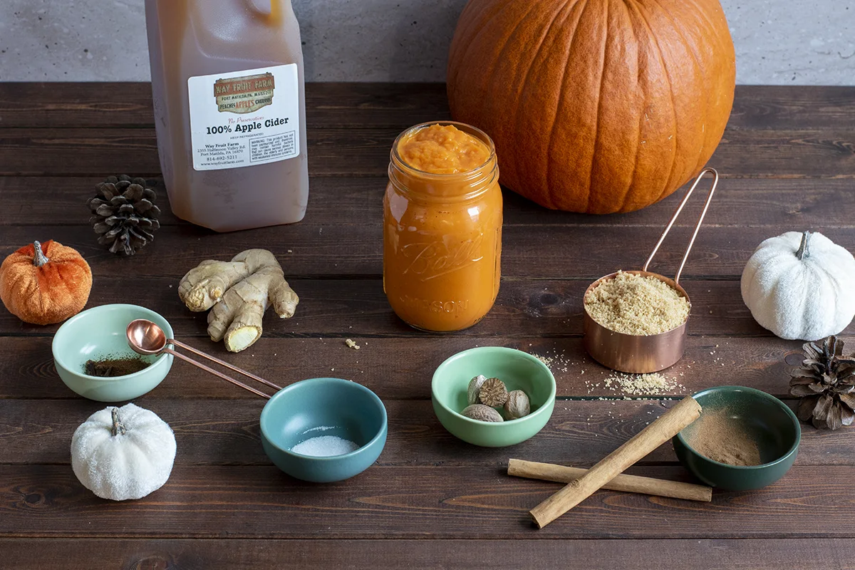Arrangement of pumpkin butter ingredients on a wood table. 