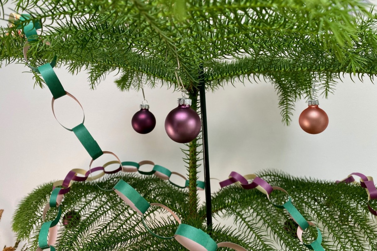 Purple and peach baubles hang from the branches of the tree. 