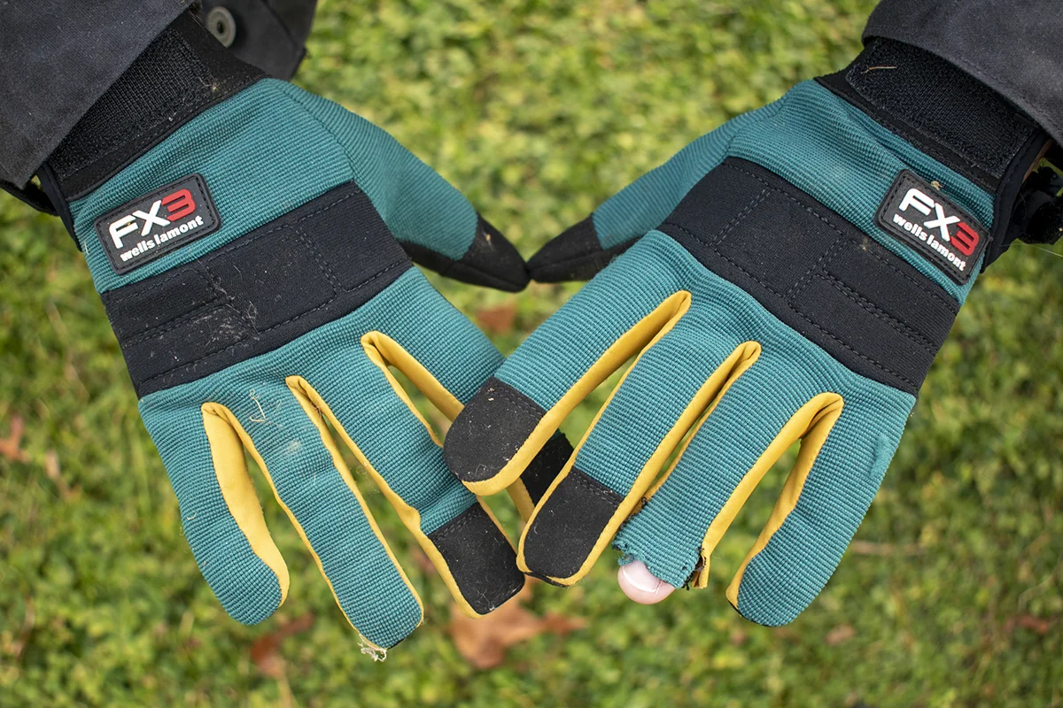Man's hands wearing gloves, one fingertip is missing on one of the gloves. 