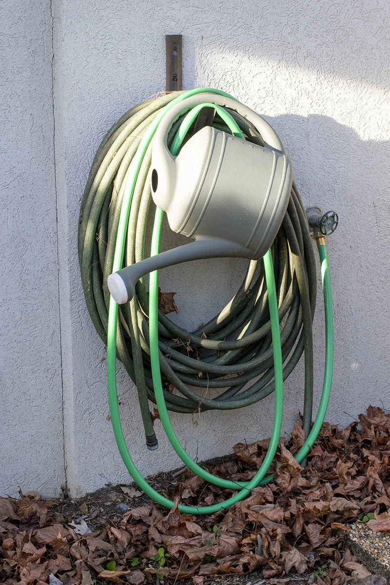 Garden hose hanging up on the side of a house.