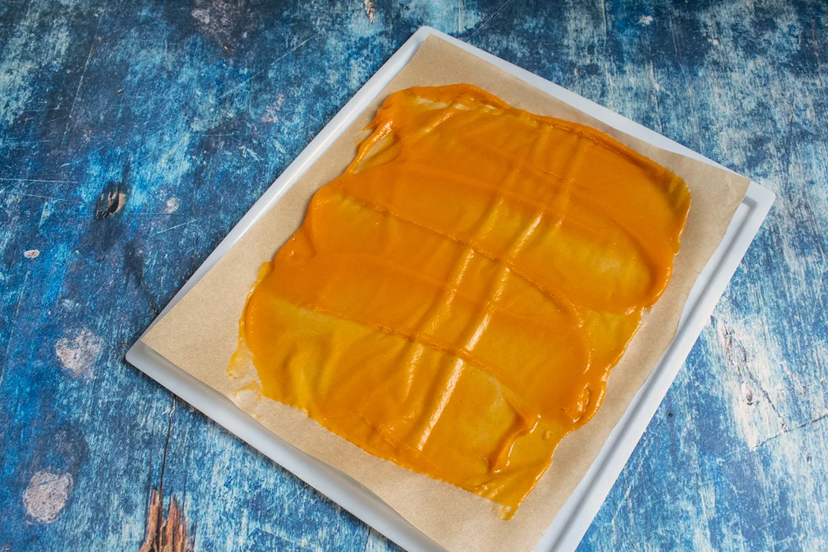 Pumpkin puree spread thinly over a parchment paper sheet.