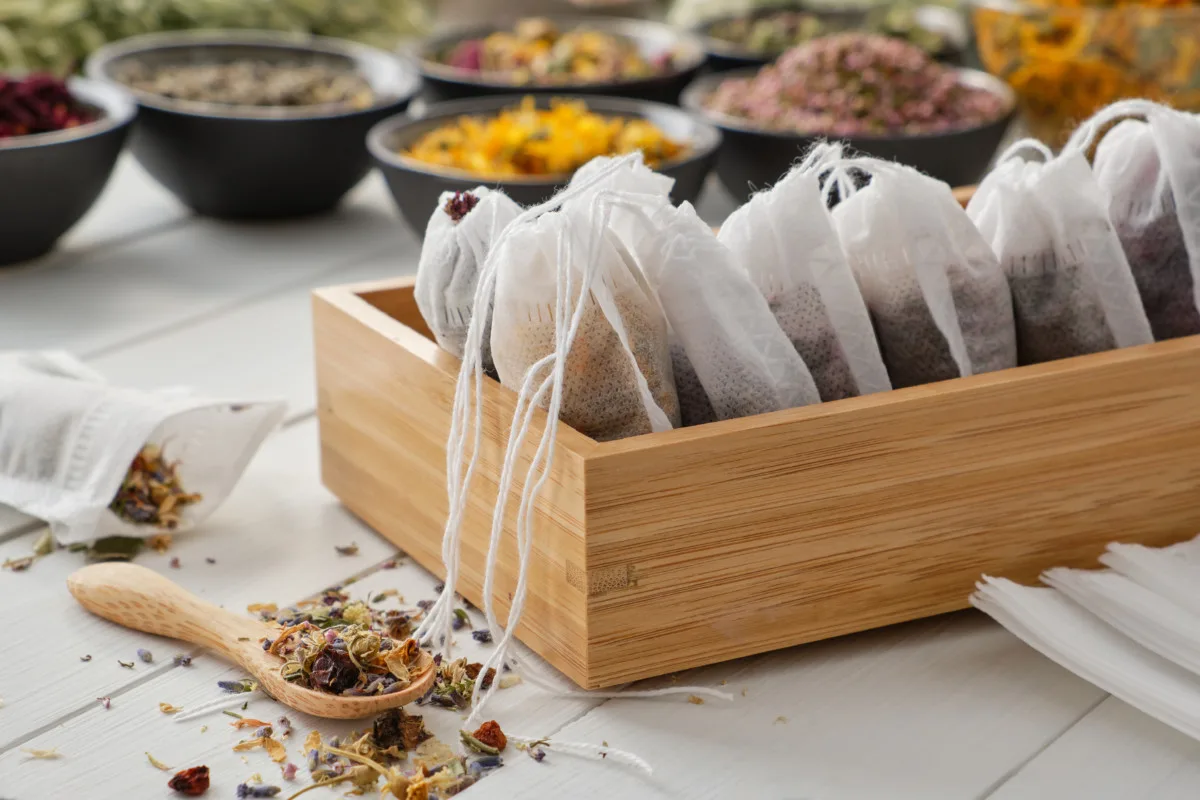 A wooden box filled with homemade herbal teas in tea bags.