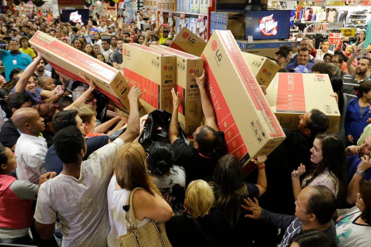 A mob of people grabbing for TVs in a store on Black Friday.