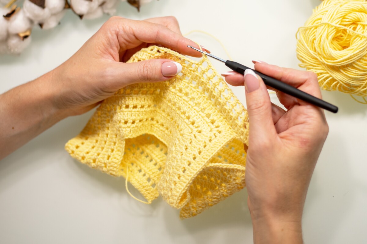 Woman's hands crocheting with yellow yarn