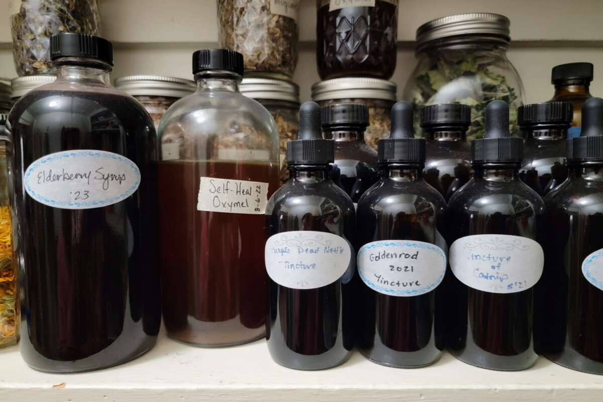 Amber colored apothecary bottles in a pantry. One of them is labelled purple dead nettle tincture