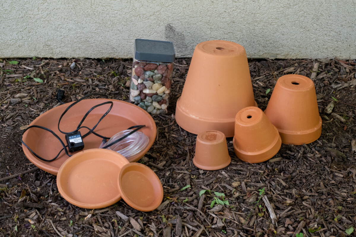 Terracotta pots and saucers in several sizes, a box of polished stones and a min submersible pump.