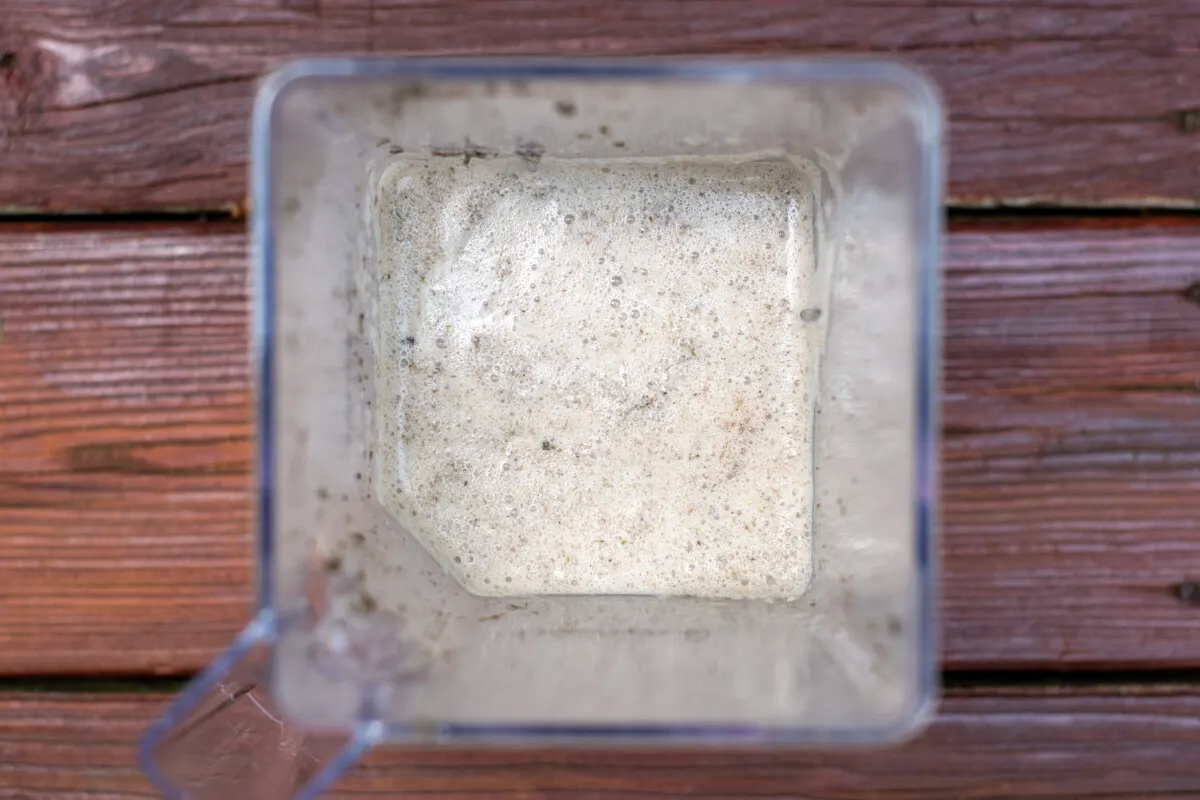 Overhead view of a blender container filled with buttermilk and moss slurry.