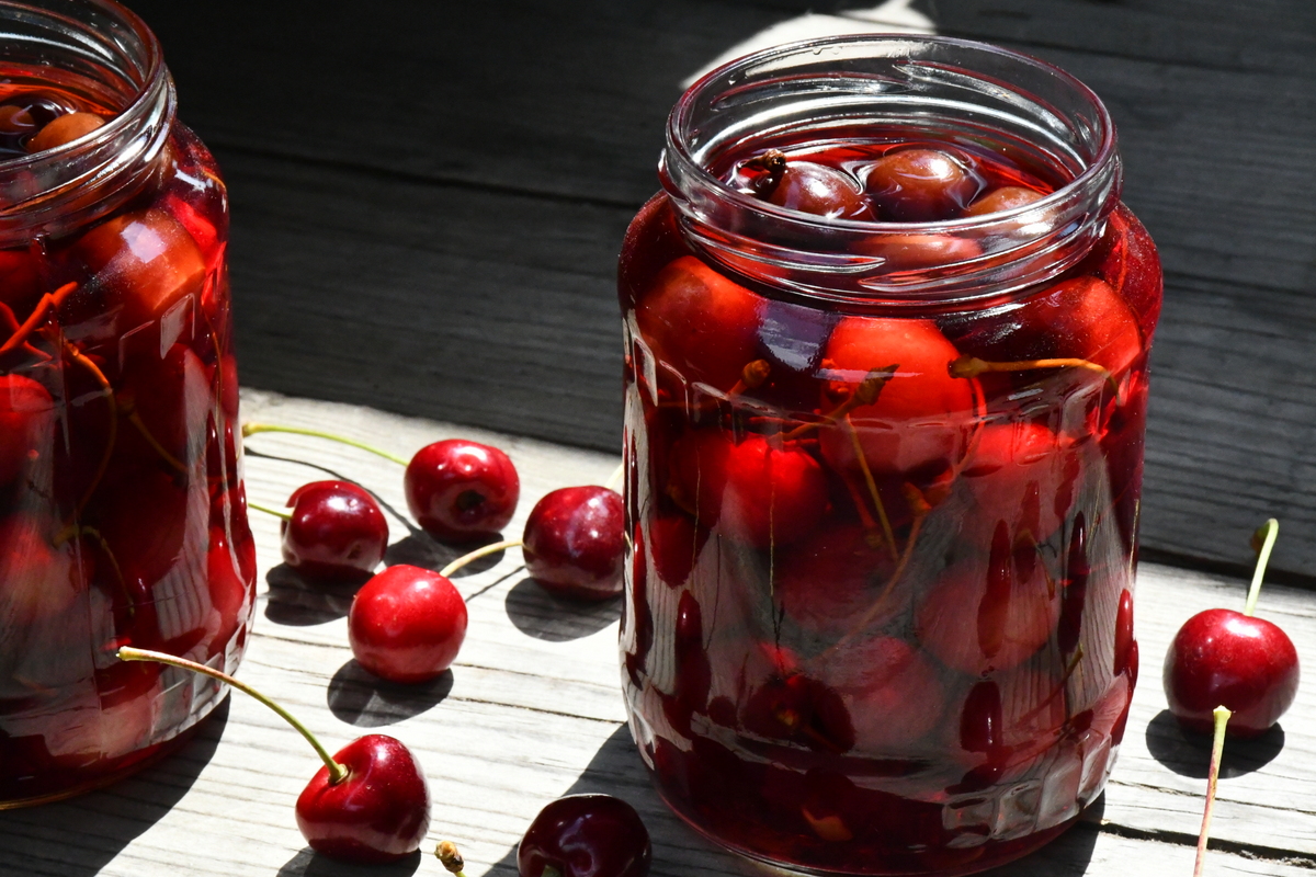 Two jars of brandied cherries in the sunshine.