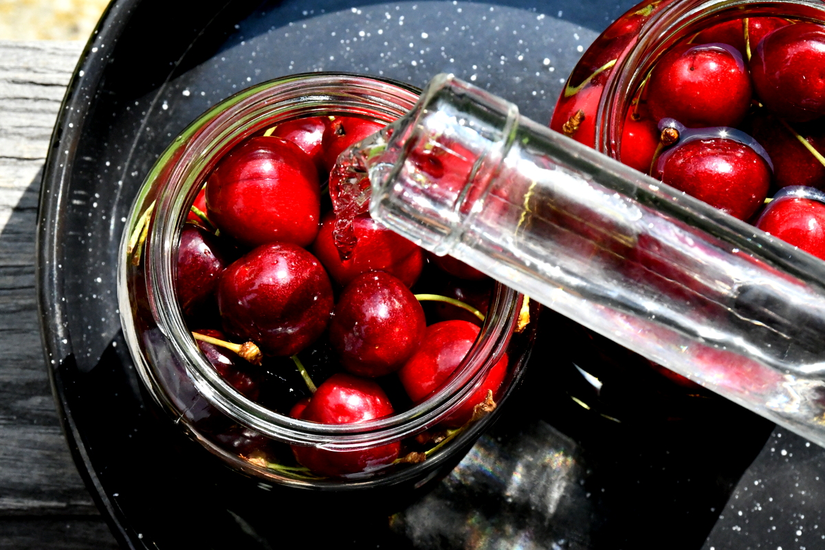 Overhead view of brandy being poured over cherries.