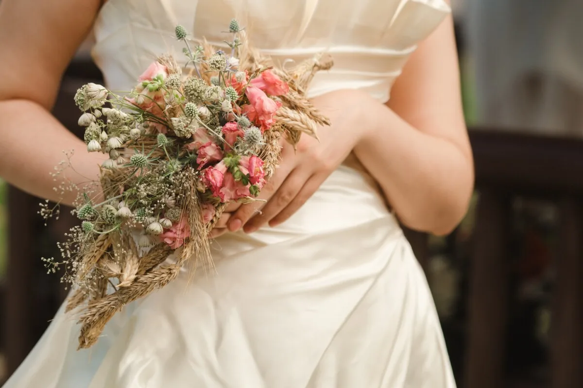 A bride carrying a dried floral arrangement