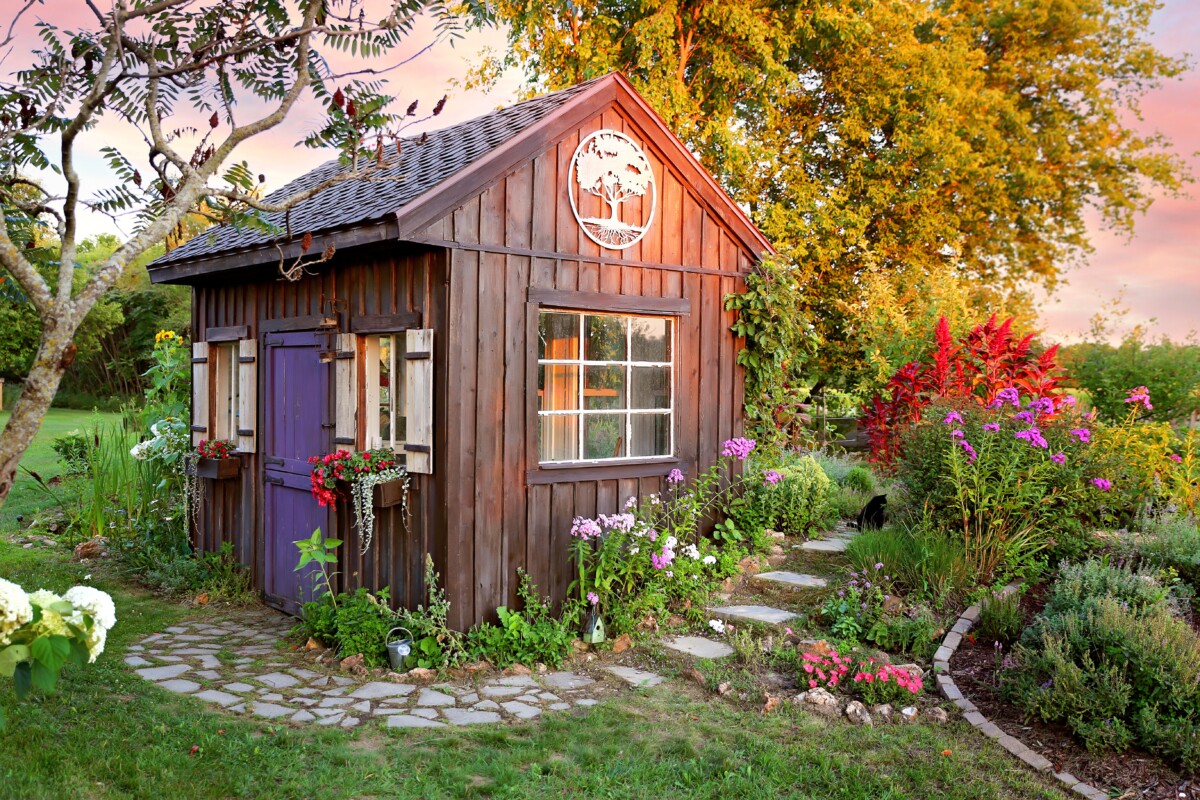Beautiful wood garden shed surrounded by flowers and trees