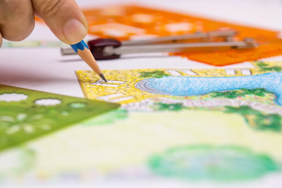 Close up of a person drawing a landscape design.