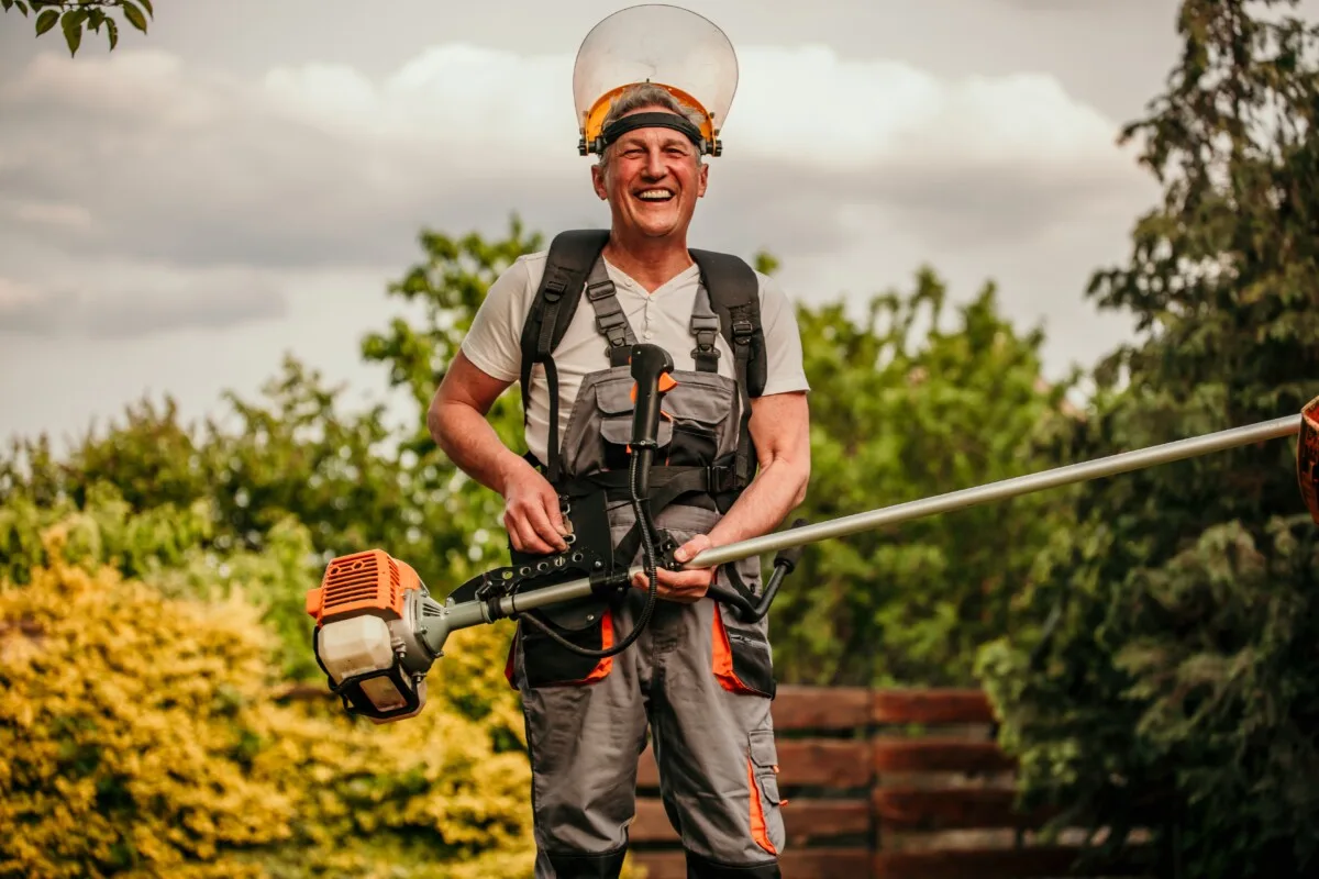 Older man kitted out with a weed whacker and PPE