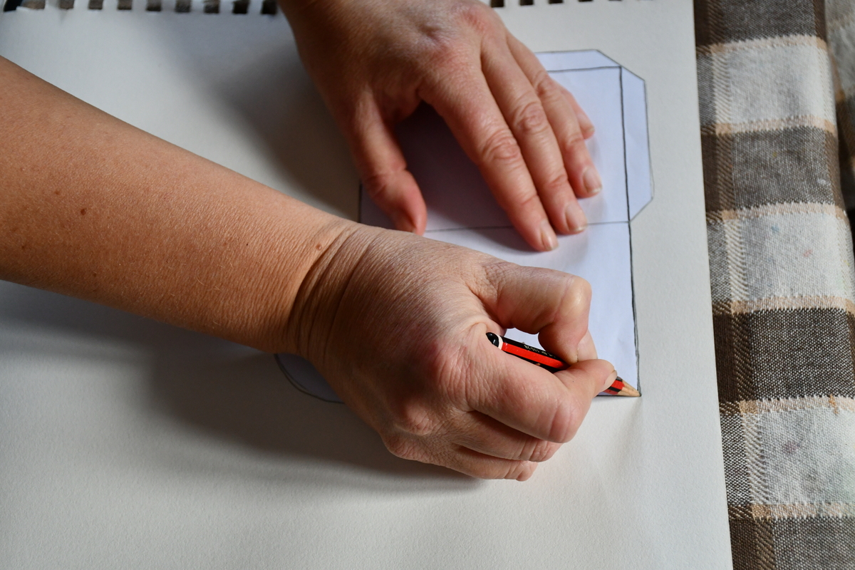 Woman's hands tracing a seed packet onto paper