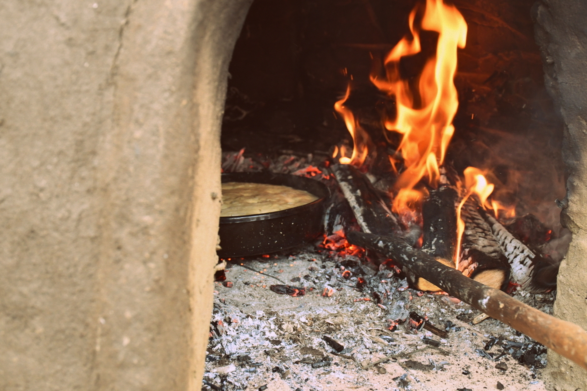 Cob oven with bread cooking inside it.