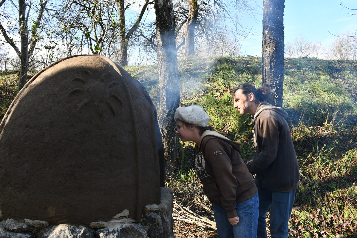 Young girl and her father looking into the cob oven