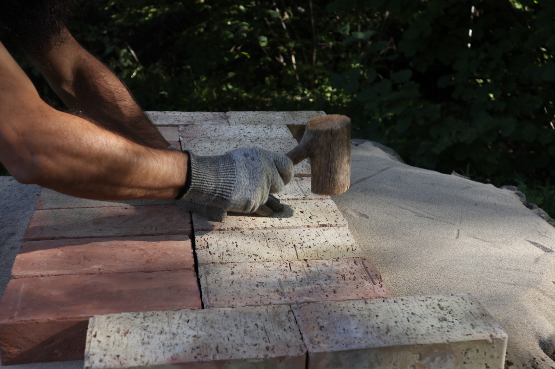 Man using homemade hammer to set bricks