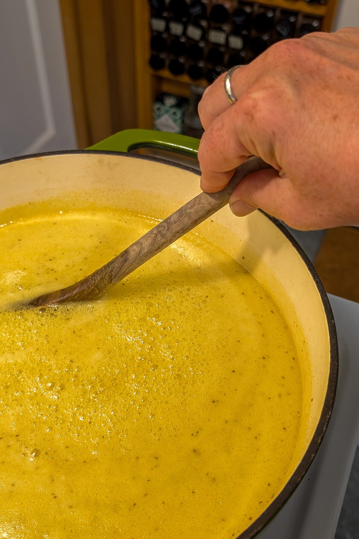 Woman's hand stirring yellow syrup.
