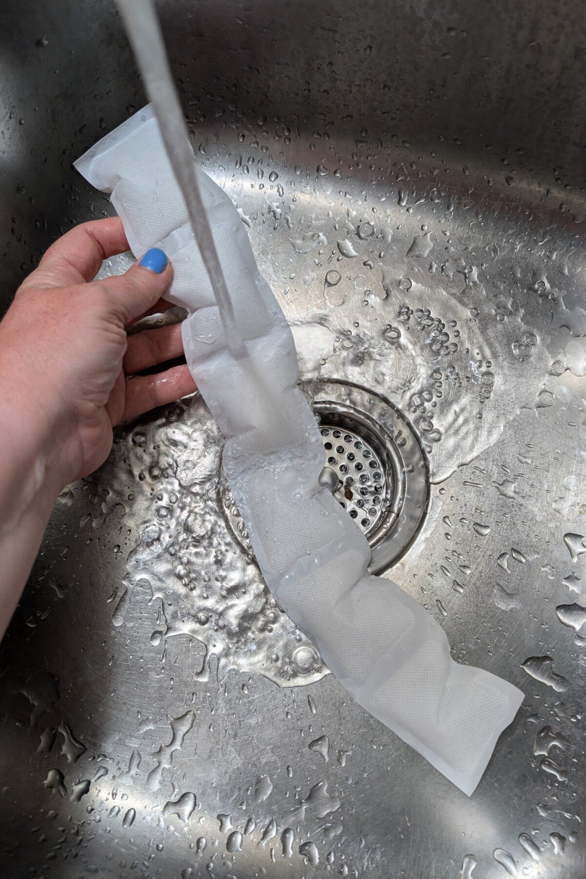 Woman's hand wetting ice pack in sink.