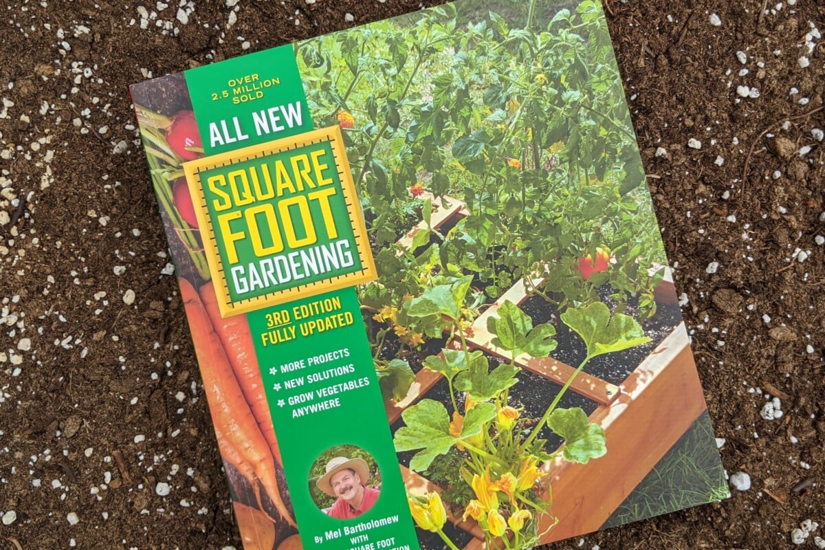 The book, All New Square Foot Gardening lying on top of soil The book, All New Square Foot Gardening lying on top of soil
