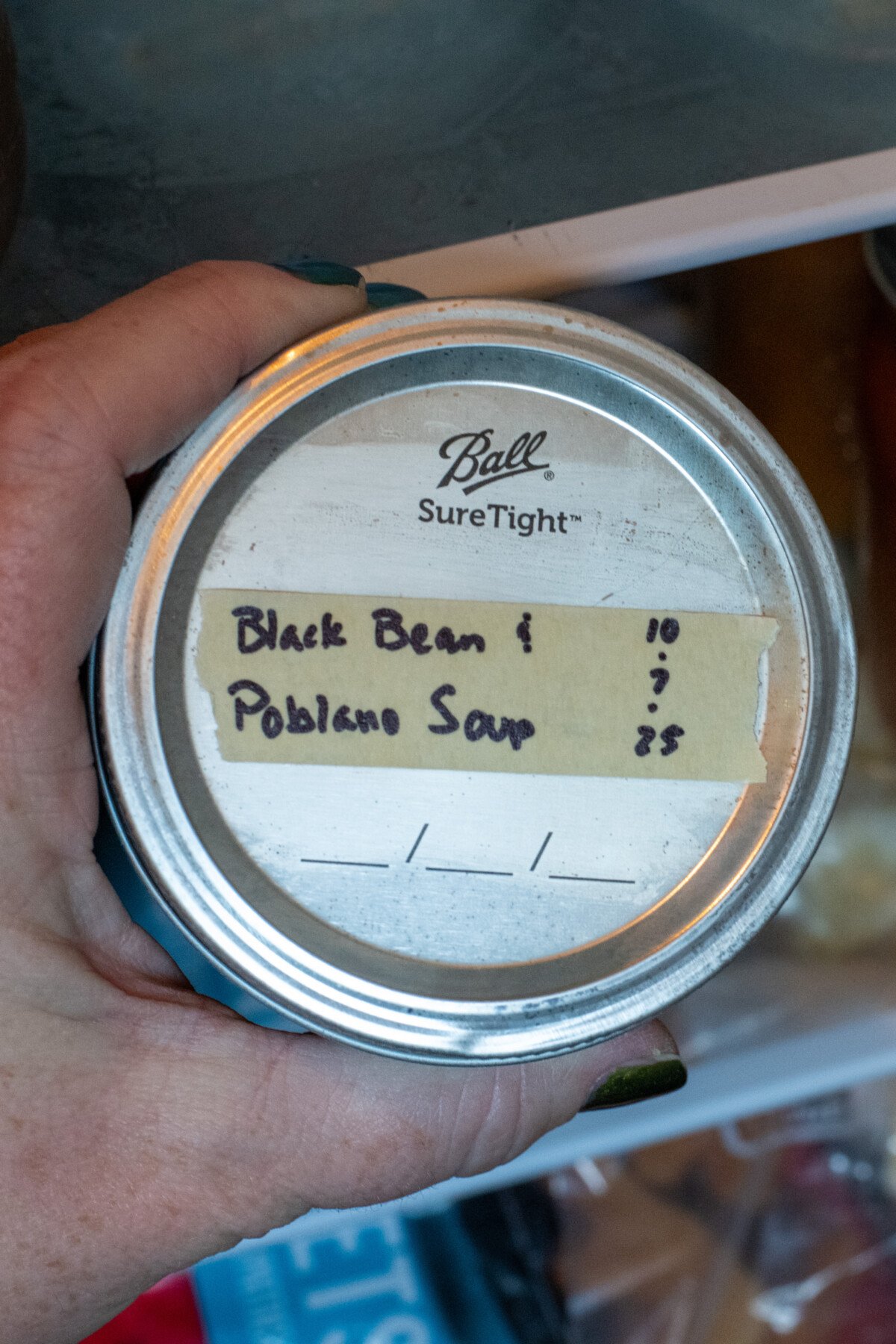 Woman's hand holding a jar of soup with a label.