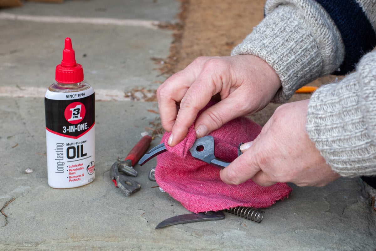 Woman's hands applying multi-purpose oil to hand pruners