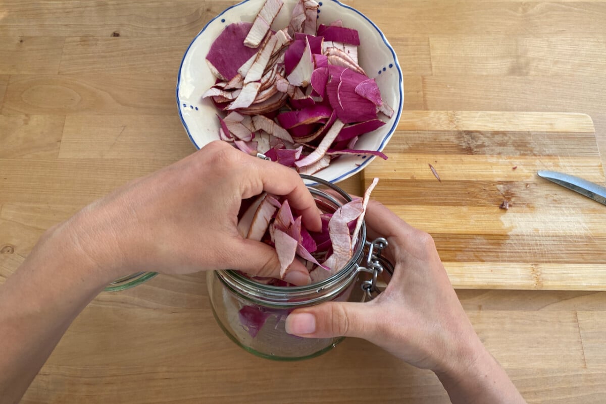 Hands putting magnolia petals in jar