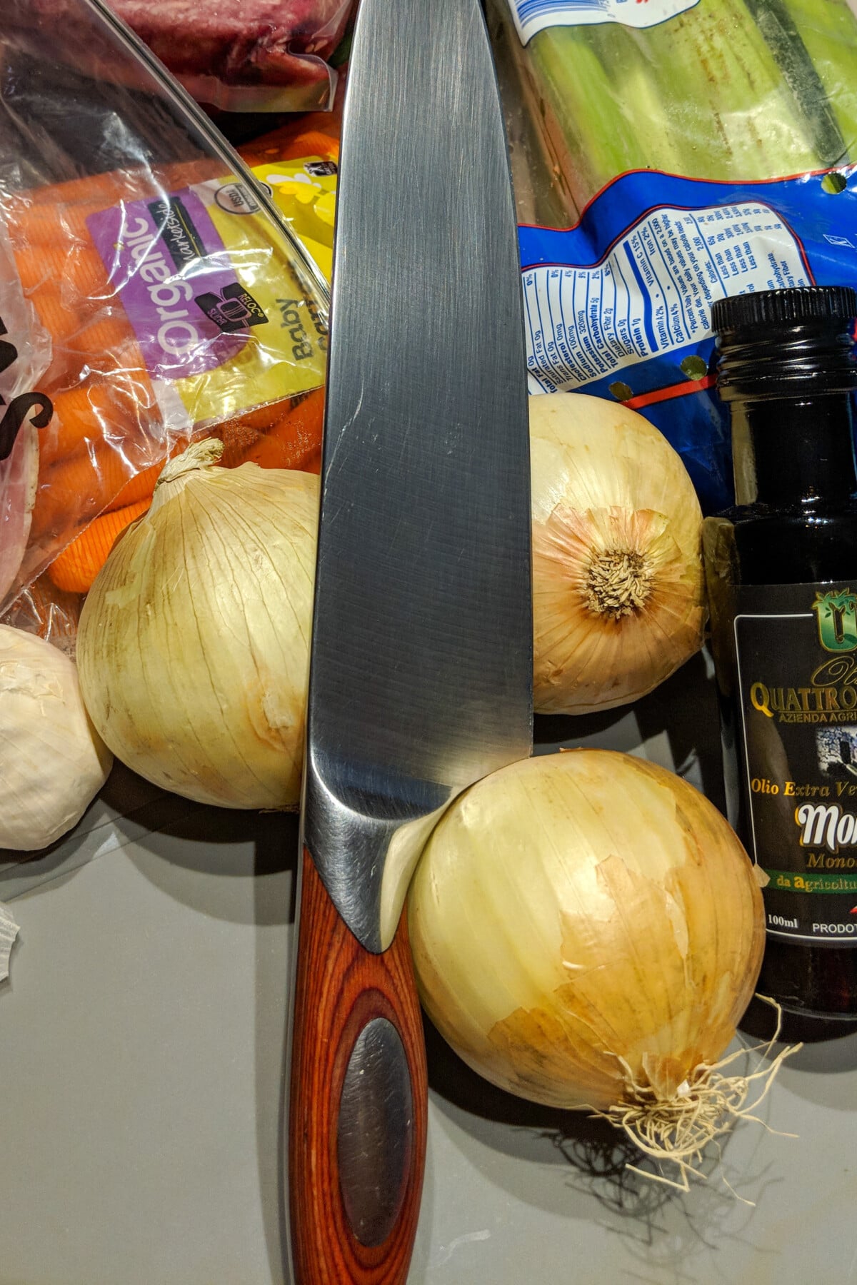 Yellow onions with a chef knife on top of them