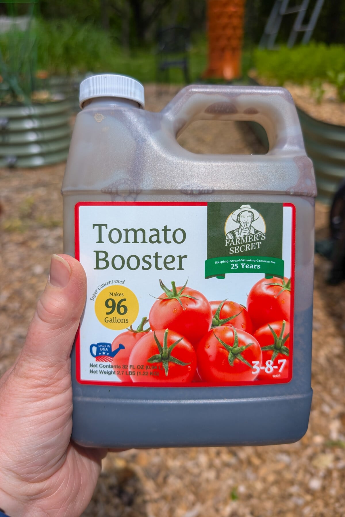 Hand holding a bottle of Farmer's Secret Tomato Booster