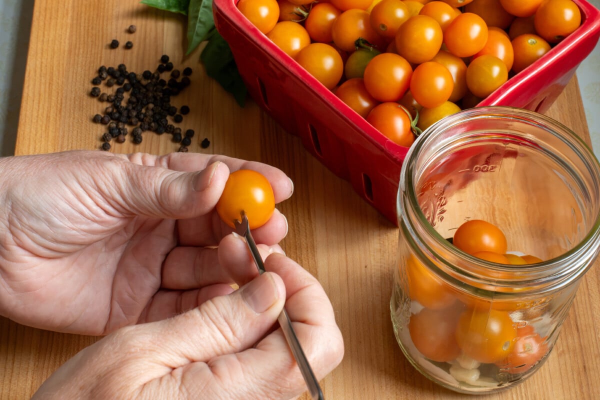 woman's hands piercing a cherry tomato with a skewer