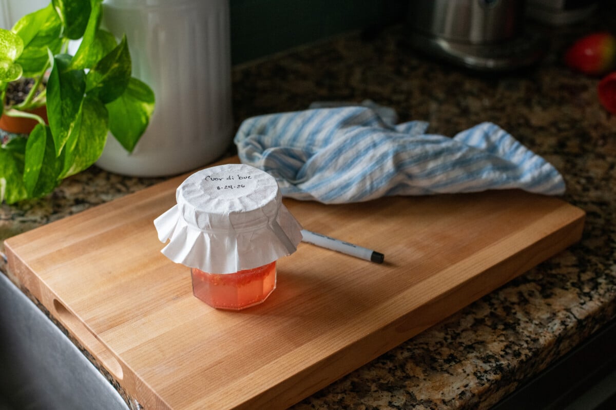jar of tomato seeds fermenting on a cutting board