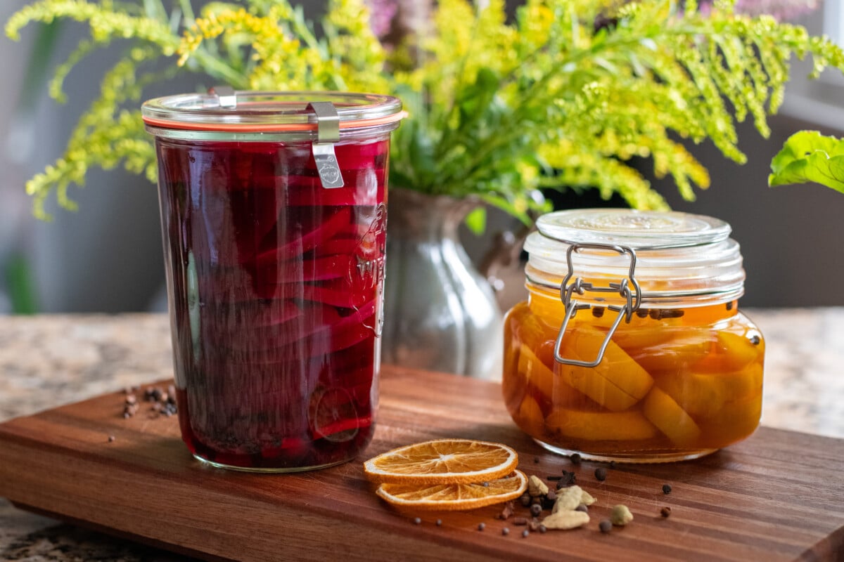 Two jars of pickled beets surrounded by pickling spices