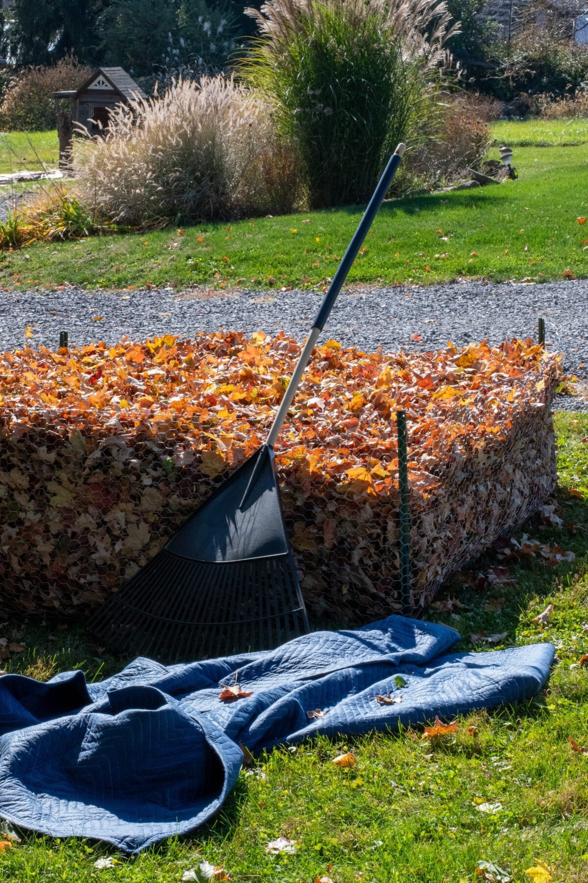 leaves in a leaf mold pen with a moving blanket and leaf rake next to it